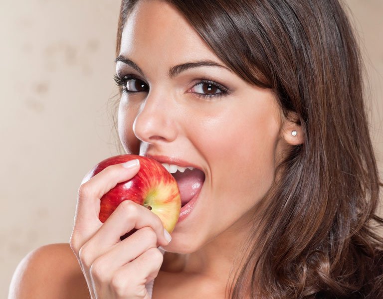 Woman biting an apple and showing healthy teeth in Stafford, VA