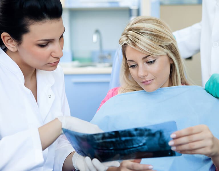 A woman and a dentist checking a dental X-ray